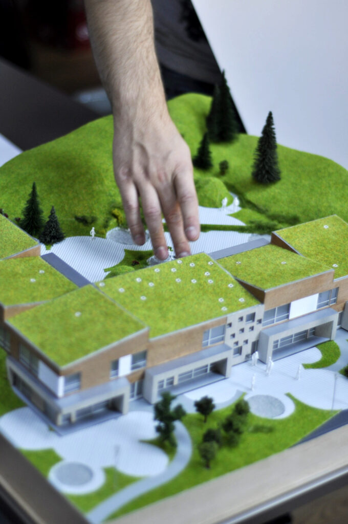 Detailed architectural model of a kindergarten by Tyark (Bergen, Norway), built into a terrain model of the surrounding fjord landscape, with precise facade and roof detailing and landscaped surroundings.